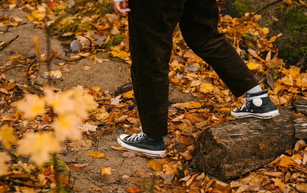 teen walking along a bed of leaves