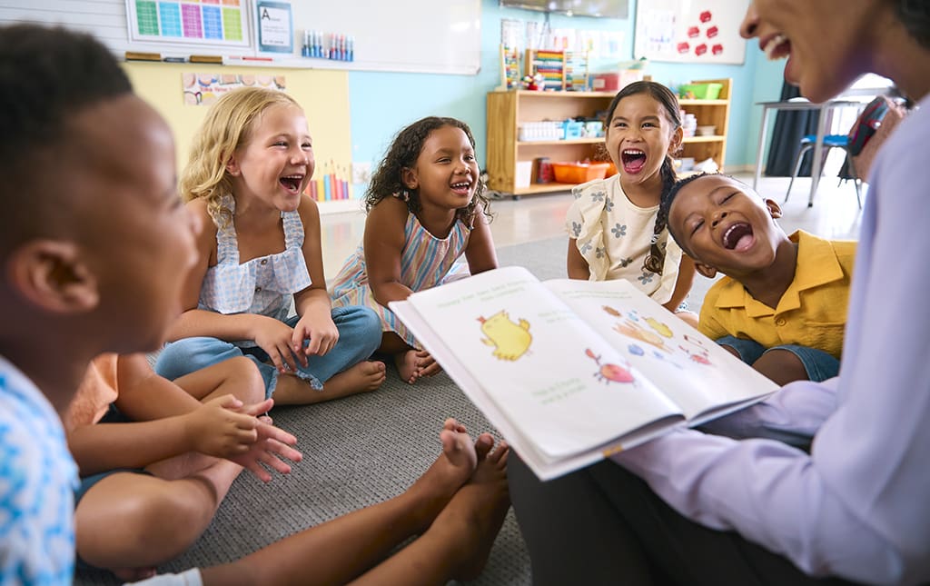 Kids listen on as their grade school teacher reads a picture book aloud.