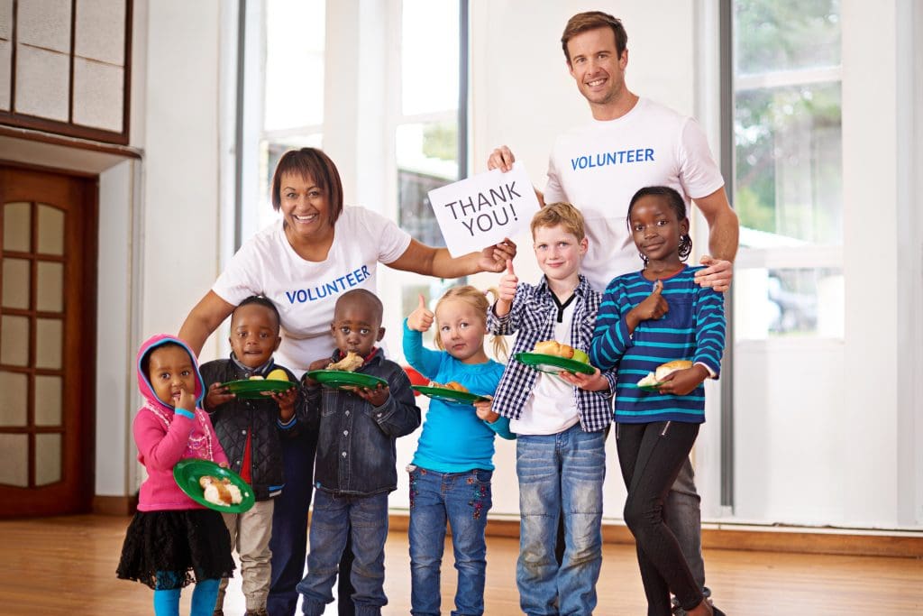 Two volunteers helping school-age kids at a fundraiser.