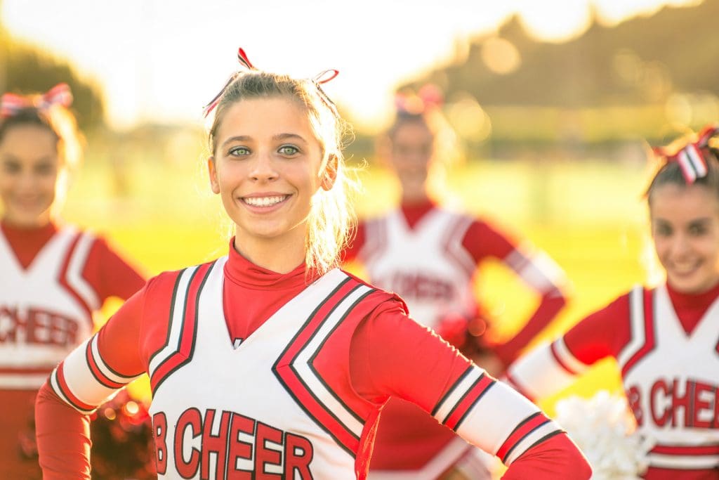 Group of school cheerleaders smiling in pose for the camera.