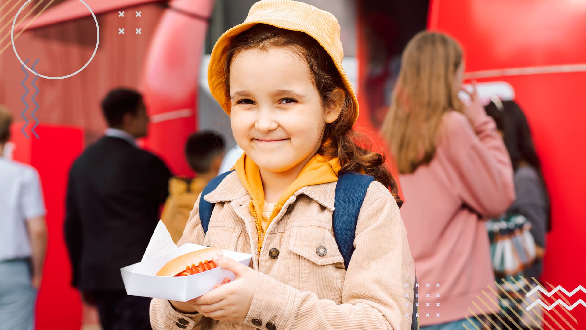 Smiling girl holding a hot dog in front of a food truck