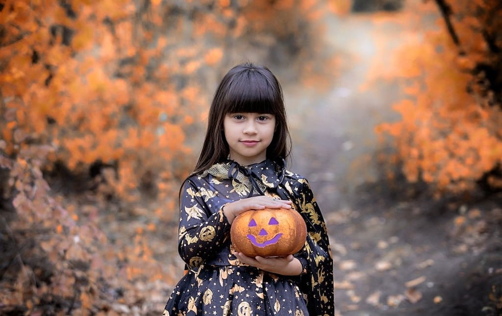 Young girl in Halloween costume holding a pumpkin