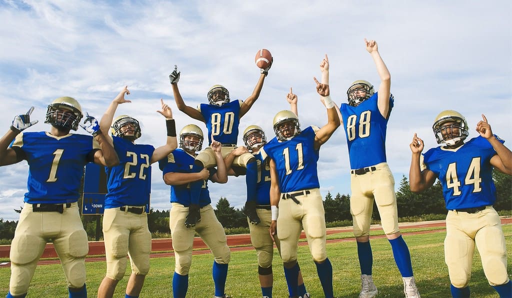 High school students celebrating on field after saving football team