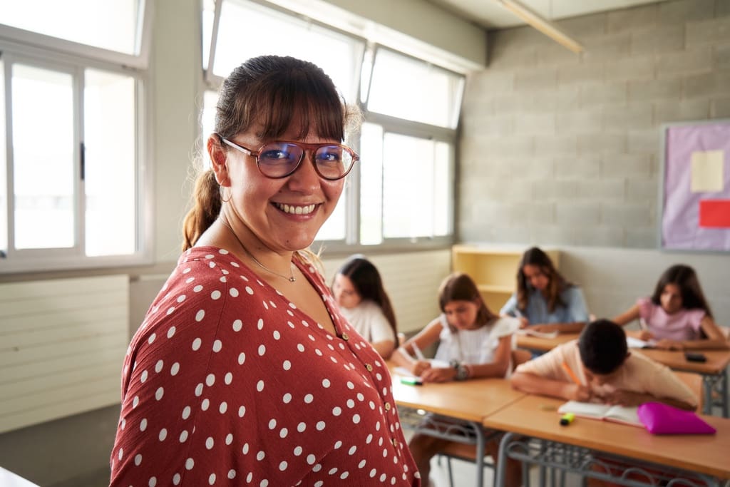 Smiling teacher with blurred board and students in background