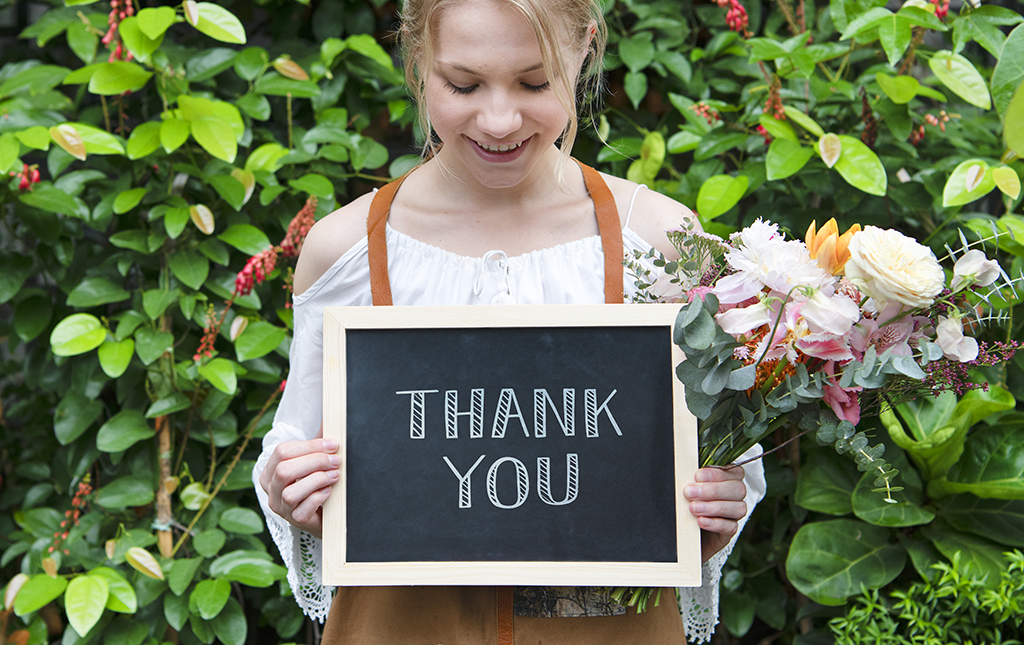 A high school girl holds up a thank you sign