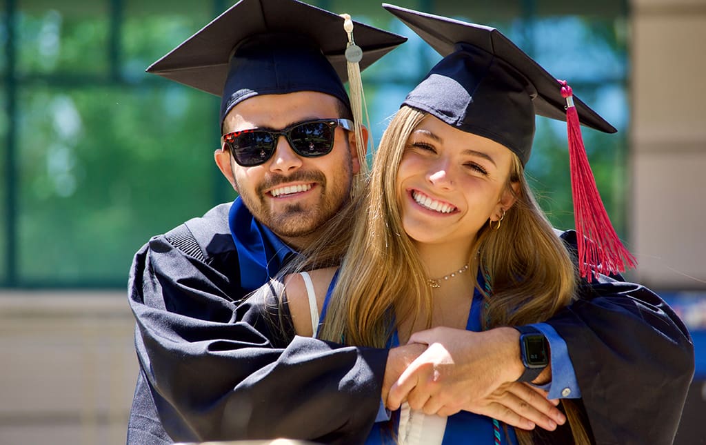 Happy graduates wearing high school graduation gowns and caps become alumni